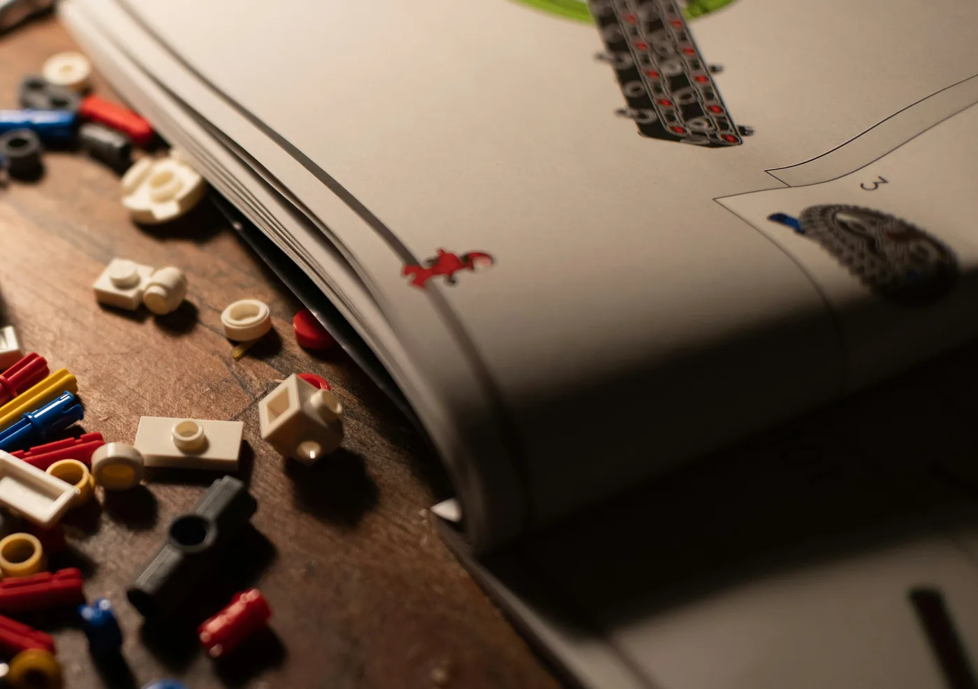 Loose LEGO pieces scattered on a wooden table beside an open instruction booklet